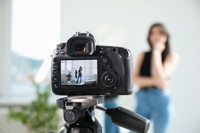 Photo of Woman near mirror in studio, focus on video camera recording her