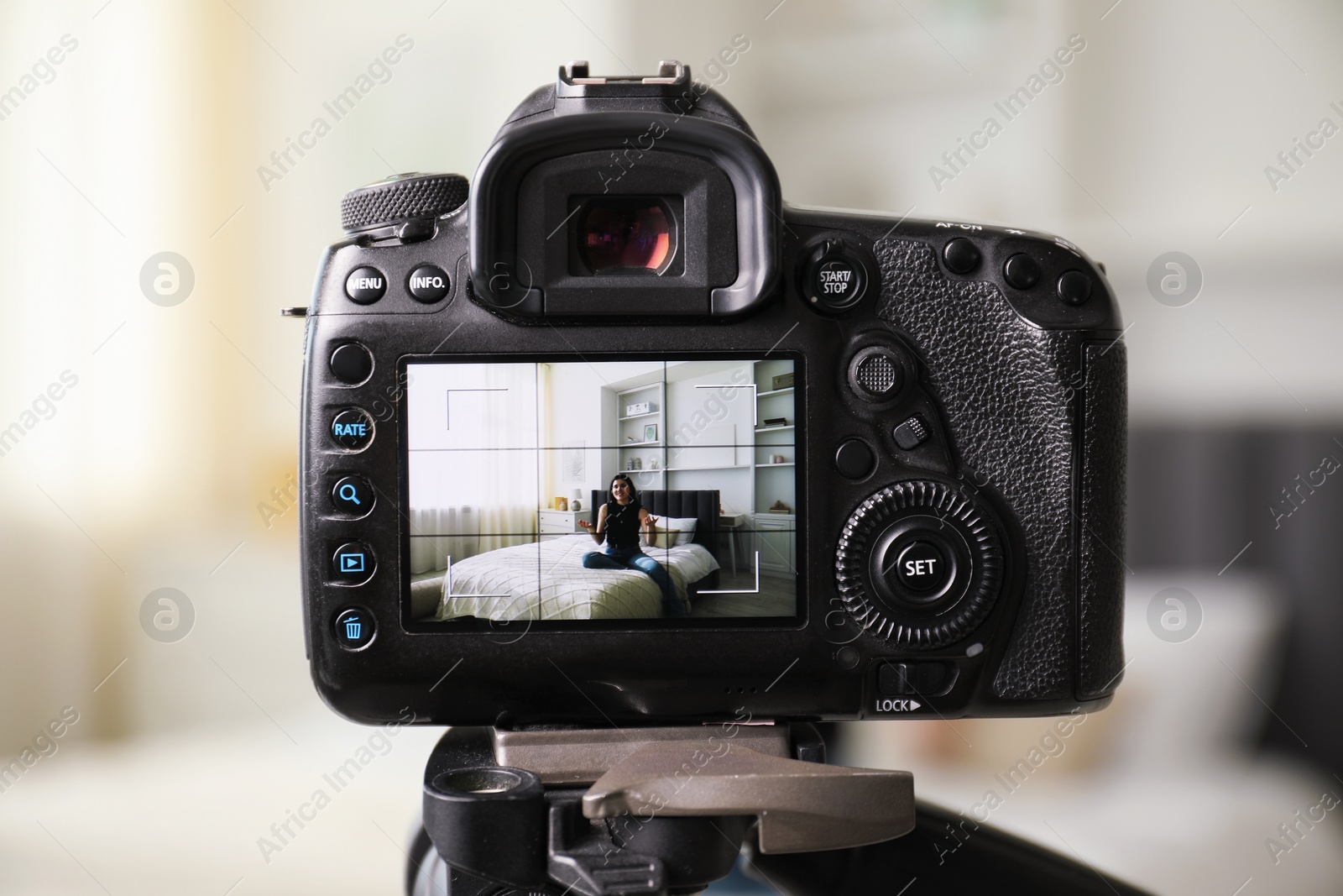 Woman sitting on bed in studio, focus on video camera recording her Photo of Woman sitting on bed in studio, focus on video camera recording her