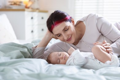 Photo of Mother putting her cute newborn baby to sleep on bed at home