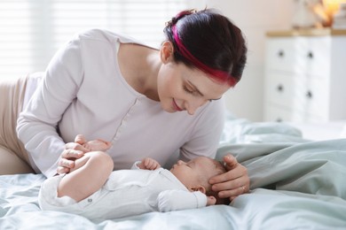 Photo of Mother putting her cute newborn baby to sleep on bed at home