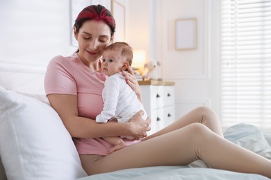 Photo of Mother putting her cute newborn baby to sleep on bed at home