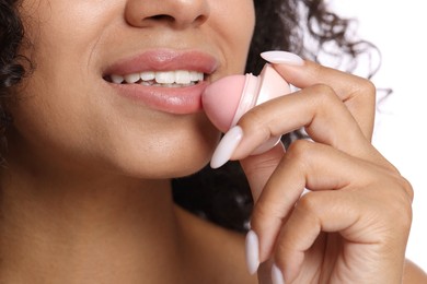 Photo of Smiling woman applying lip balm onto her lips on white background, closeup