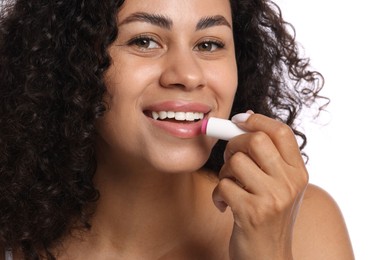 Photo of Smiling woman applying lip balm onto her lips on white background, closeup