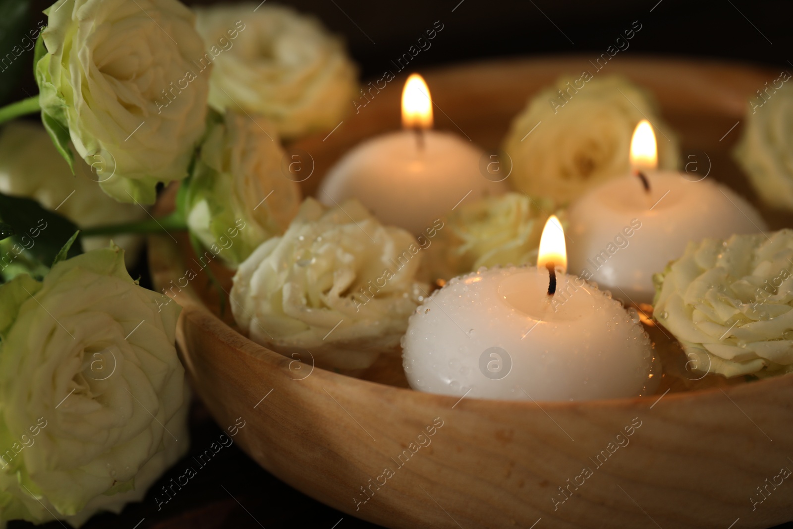 Burning candles, water and rose flowers in bowl on wooden table, closeup Photo of Burning candles, water and rose flowers in bowl on wooden table, closeup