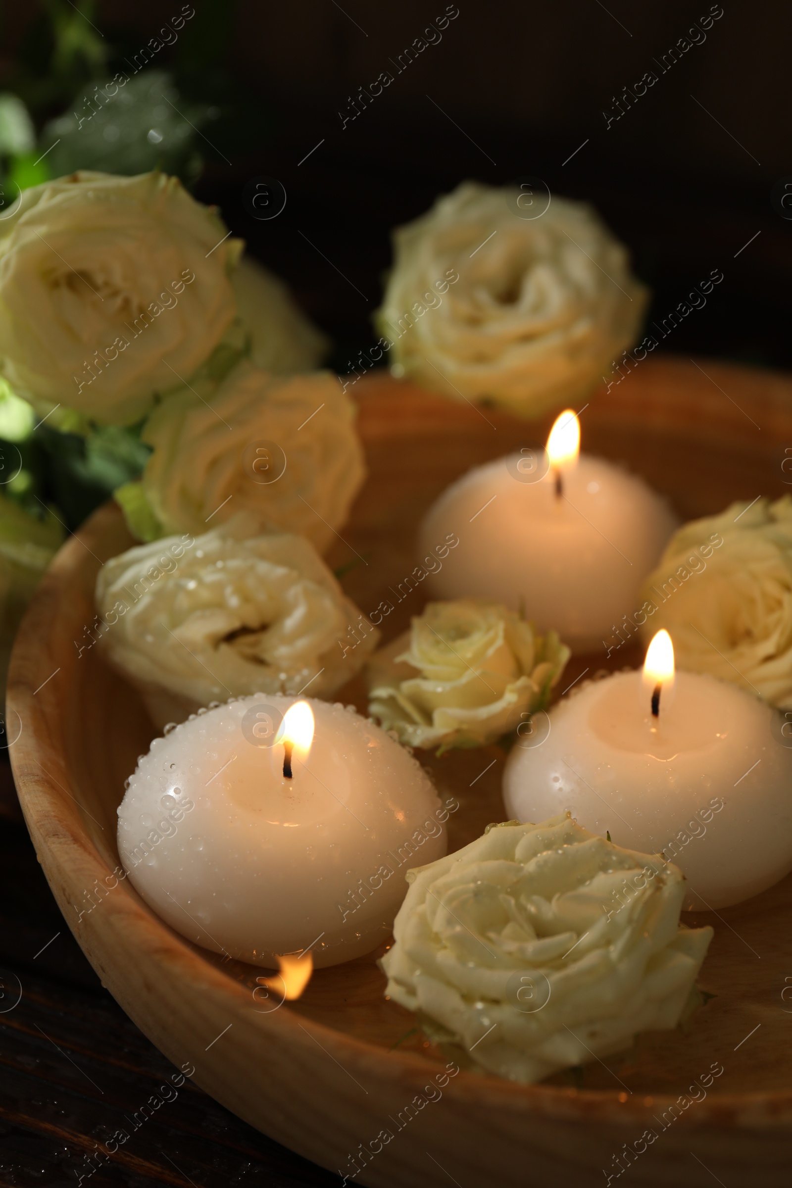 Burning candles, water and rose flowers in bowl on wooden table, closeup Photo of Burning candles, water and rose flowers in bowl on wooden table, closeup