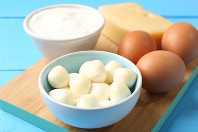 Photo of Different dairy products and eggs on light blue wooden table, closeup