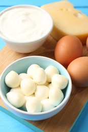 Photo of Different dairy products and eggs on light blue table, above view