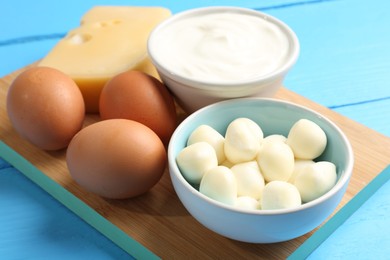 Photo of Different dairy products and eggs on light blue wooden table, closeup