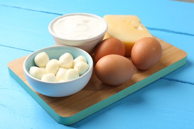 Photo of Different dairy products and eggs on light blue wooden table, closeup