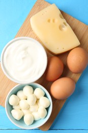 Photo of Different dairy products and eggs on light blue wooden table, top view