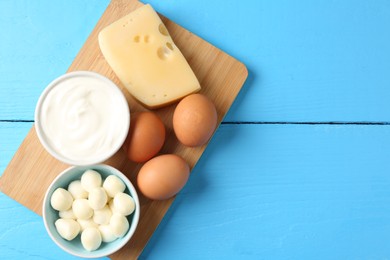Photo of Different dairy products and eggs on light blue wooden table, top view. Space for text