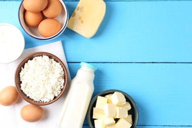 Photo of Different dairy products and eggs on light blue wooden table, flat lay. Space for text