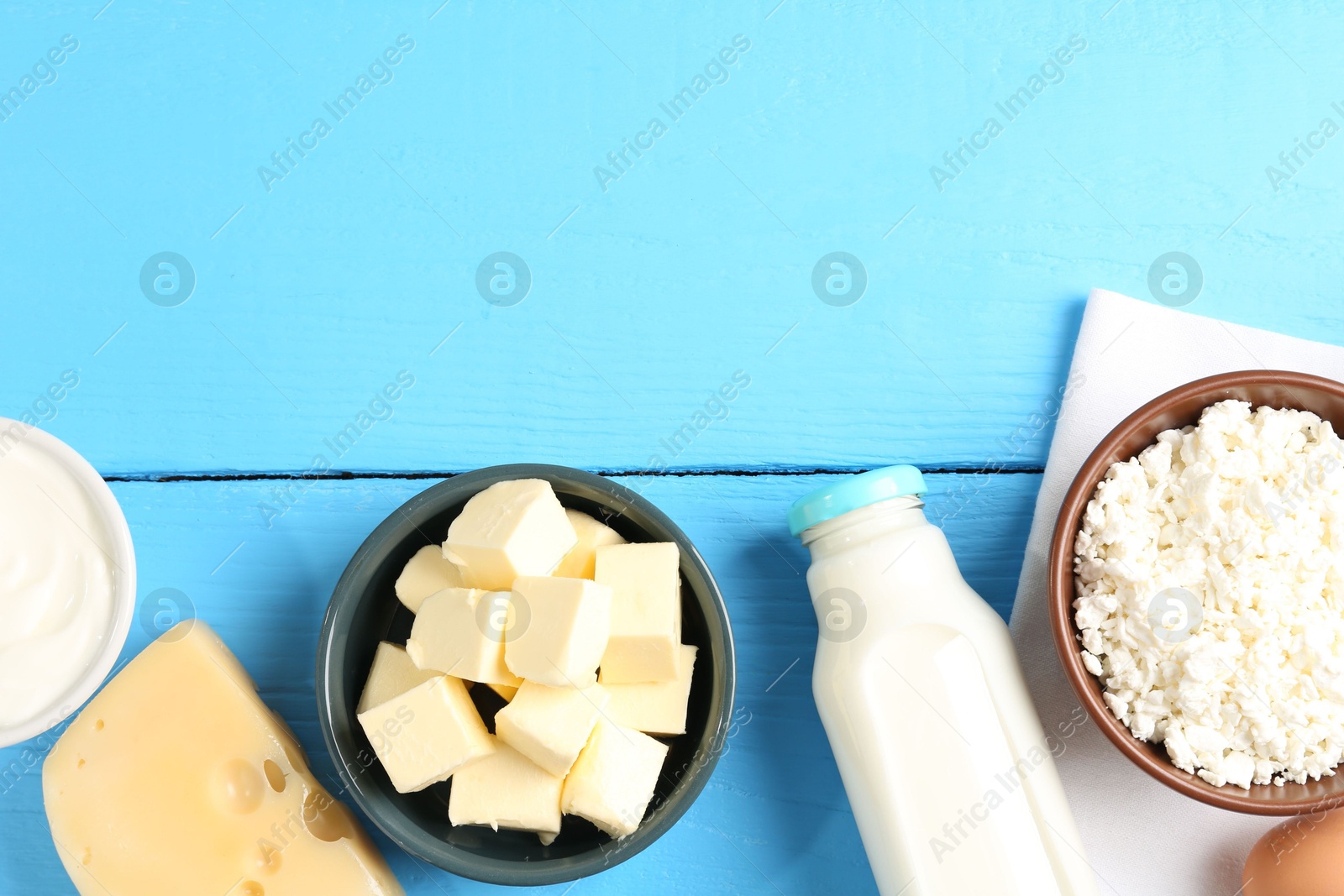 Photo of Different dairy products on light blue wooden table, flat lay. Space for text