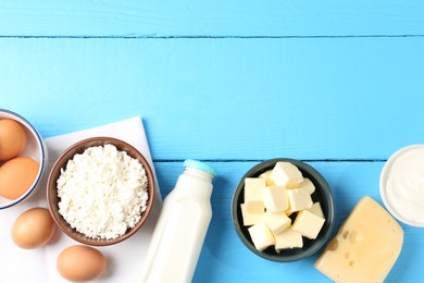 Photo of Different dairy products and eggs on light blue wooden table, flat lay. Space for text