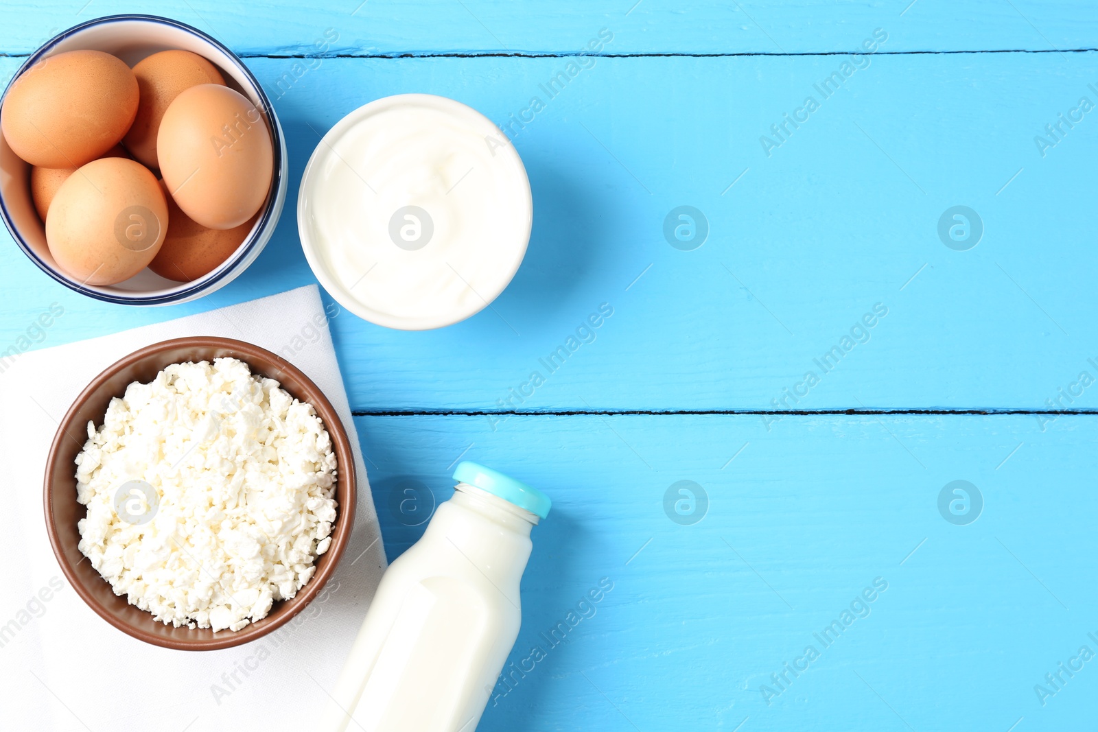 Different dairy products and eggs on light blue wooden table, flat lay. Space for text Photo of Different dairy products and eggs on light blue wooden table, flat lay. Space for text