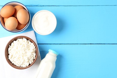 Photo of Different dairy products and eggs on light blue wooden table, flat lay. Space for text