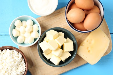 Photo of Different dairy products and eggs on light blue wooden table, flat lay