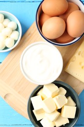 Photo of Different dairy products and eggs on light blue wooden table, flat lay