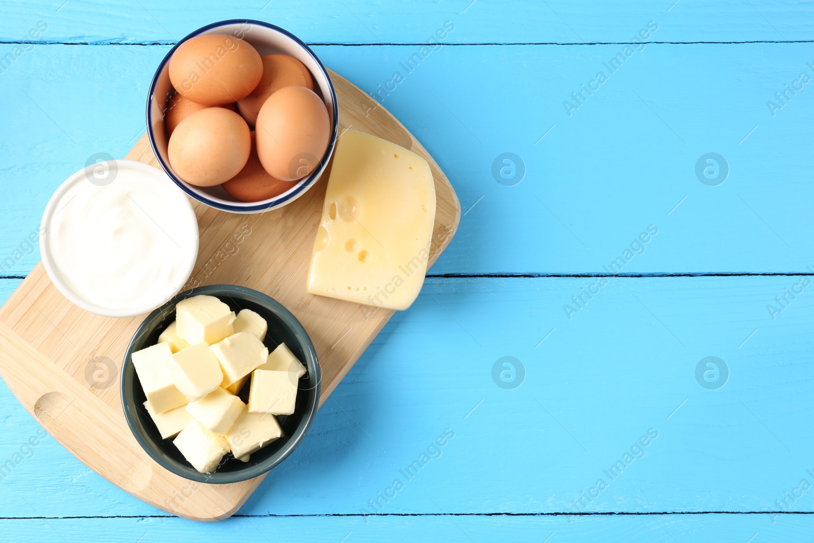 Different dairy products and eggs on light blue wooden table, flat lay. Space for text Photo of Different dairy products and eggs on light blue wooden table, flat lay. Space for text