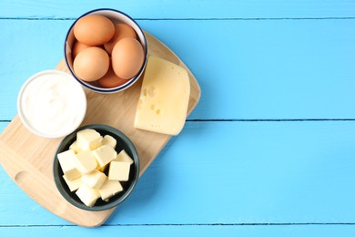 Photo of Different dairy products and eggs on light blue wooden table, flat lay. Space for text