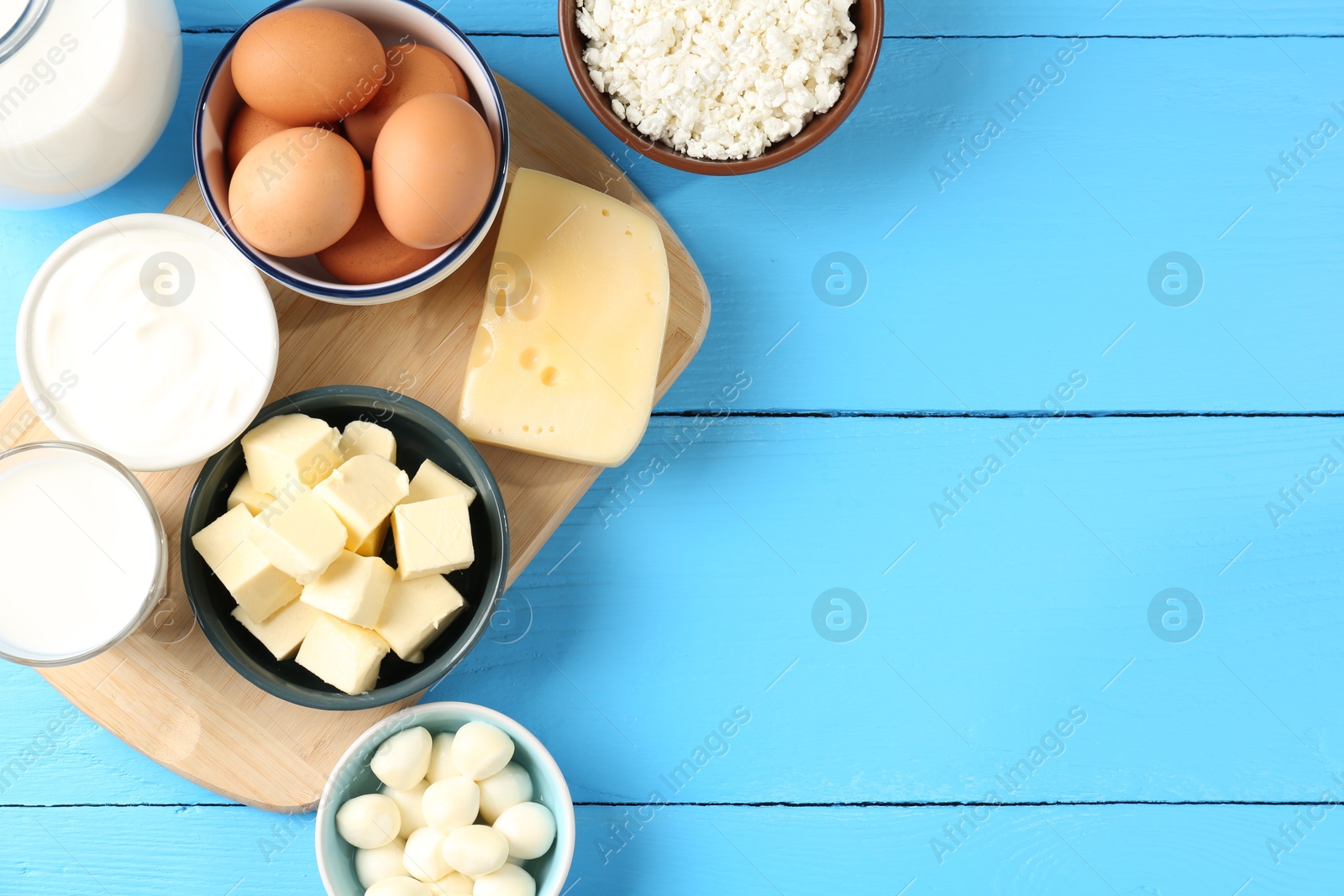 Different dairy products and eggs on light blue wooden table, flat lay. Space for text Photo of Different dairy products and eggs on light blue wooden table, flat lay. Space for text