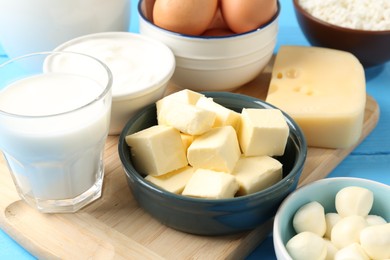 Photo of Different dairy products and eggs on light blue table, closeup
