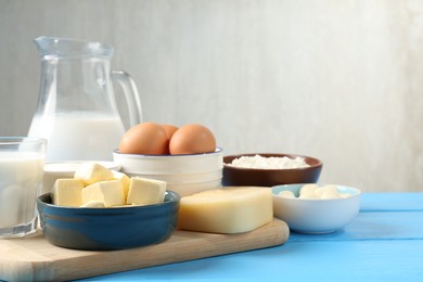 Photo of Different dairy products and eggs on light blue wooden table, closeup. Space for text