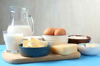 Photo of Different dairy products and eggs on light blue wooden table