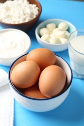 Photo of Different dairy products and eggs on light blue wooden table, above view