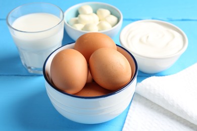 Photo of Different dairy products and eggs on light blue wooden table, closeup