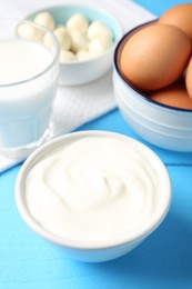 Photo of Different dairy products and eggs on light blue wooden table, closeup
