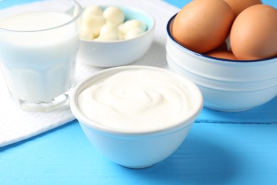 Photo of Different dairy products and eggs on light blue wooden table, closeup