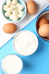 Photo of Different dairy products and eggs on light blue wooden table, flat lay