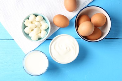 Photo of Different dairy products and eggs on light blue wooden table, flat lay