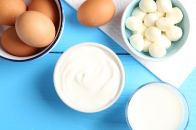 Photo of Different dairy products and eggs on light blue wooden table, flat lay