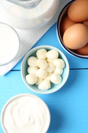 Photo of Different dairy products and eggs on light blue wooden table, flat lay