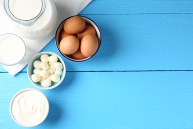 Photo of Different dairy products and eggs on light blue wooden table, flat lay. Space for text