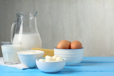 Photo of Different dairy products and eggs on light blue wooden table, space for text