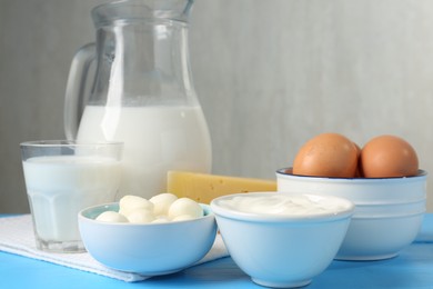 Photo of Different dairy products and eggs on light blue wooden table, closeup