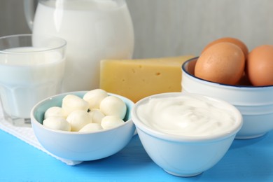 Photo of Different dairy products and eggs on light blue wooden table, closeup