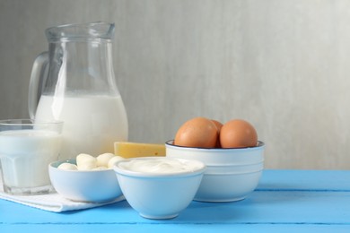 Photo of Different dairy products and eggs on light blue wooden table, space for text