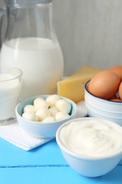 Photo of Different dairy products and eggs on light blue wooden table, closeup