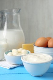 Photo of Different dairy products and eggs on light blue wooden table, closeup