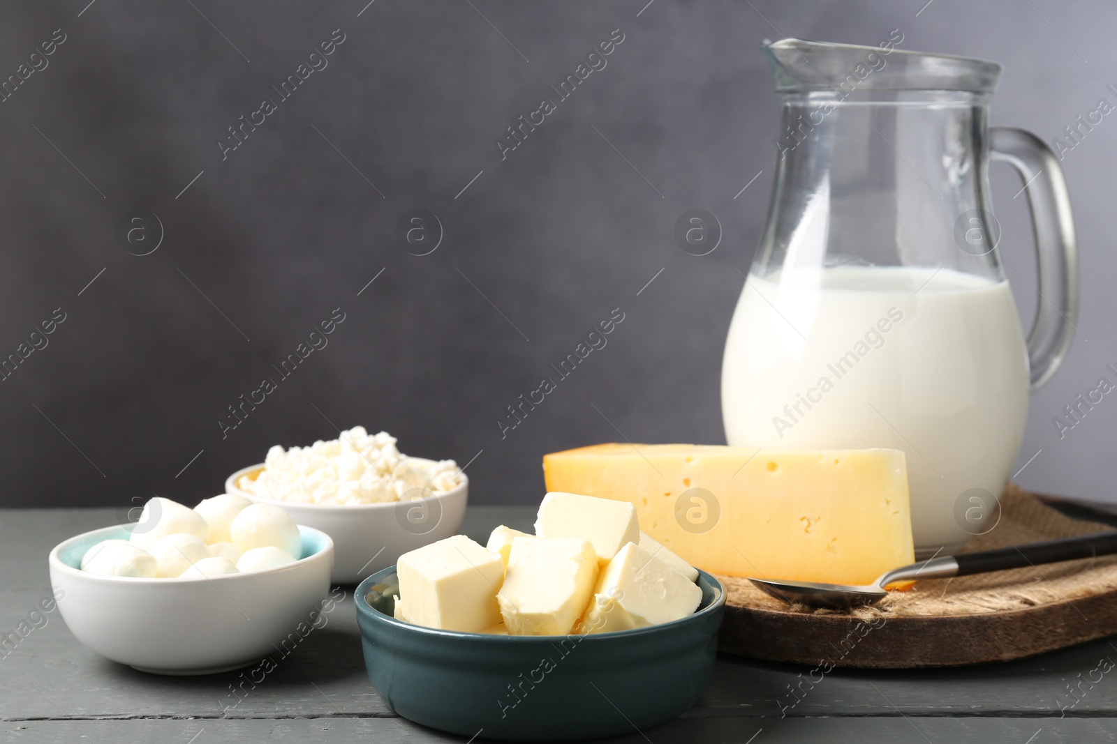 Photo of Different dairy products on grey wooden table, closeup