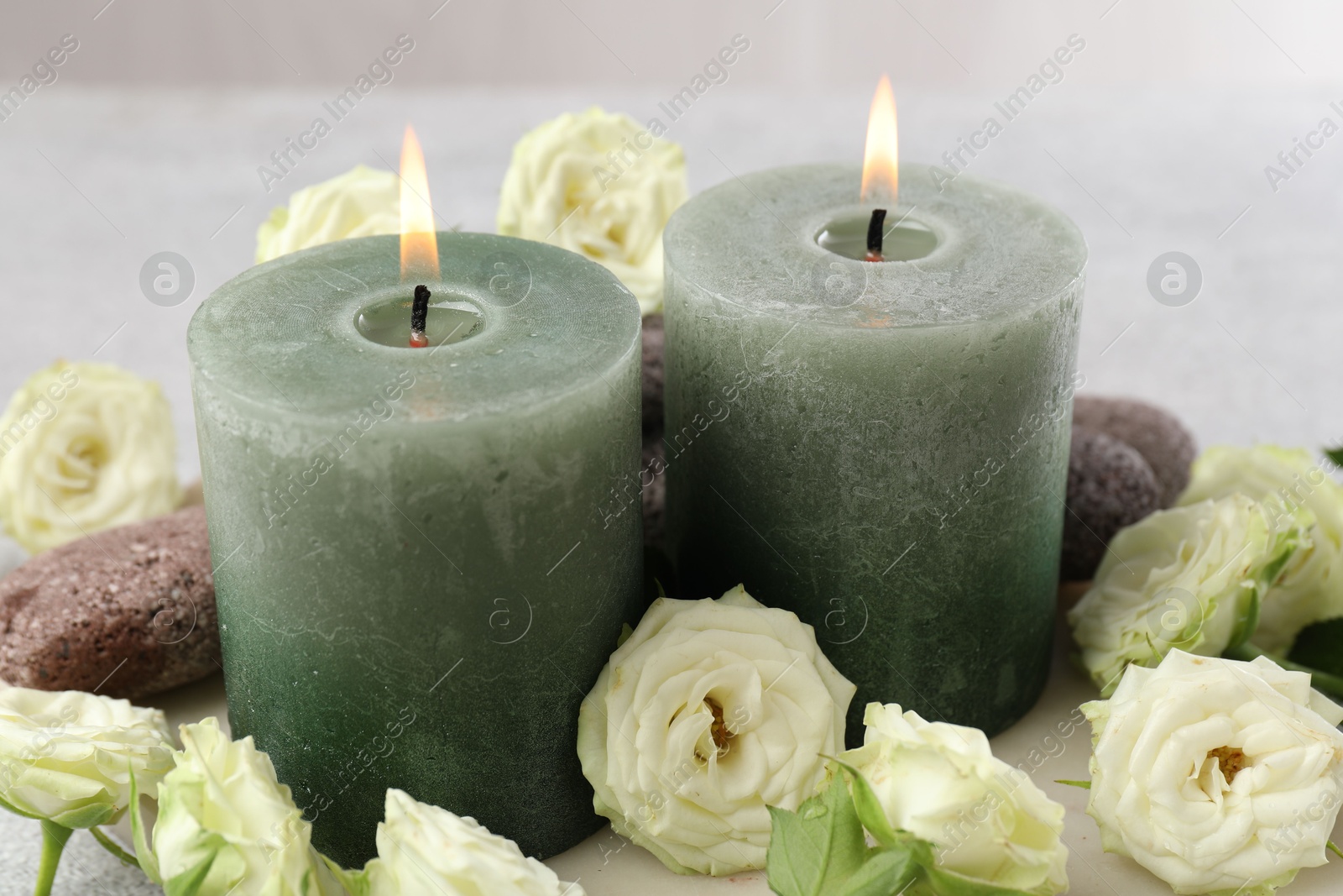Burning candles, stones and rose flowers on table, closeup Photo of Burning candles, stones and rose flowers on table, closeup