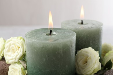Photo of Burning candles, stones and rose flowers on table, closeup