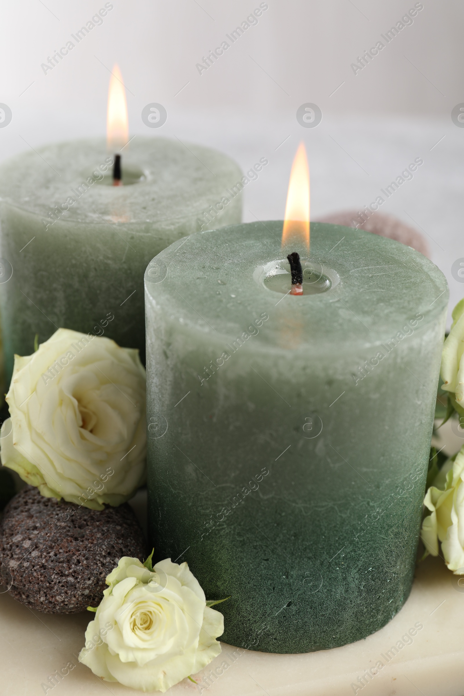 Photo of Burning candles, stones and rose flowers on table, closeup