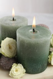 Photo of Burning candles, stones and rose flowers on table, closeup