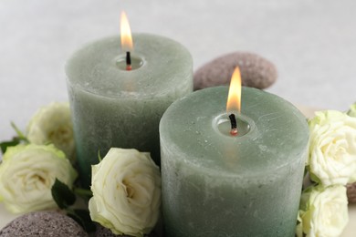 Photo of Burning candles, stones and rose flowers on table, closeup