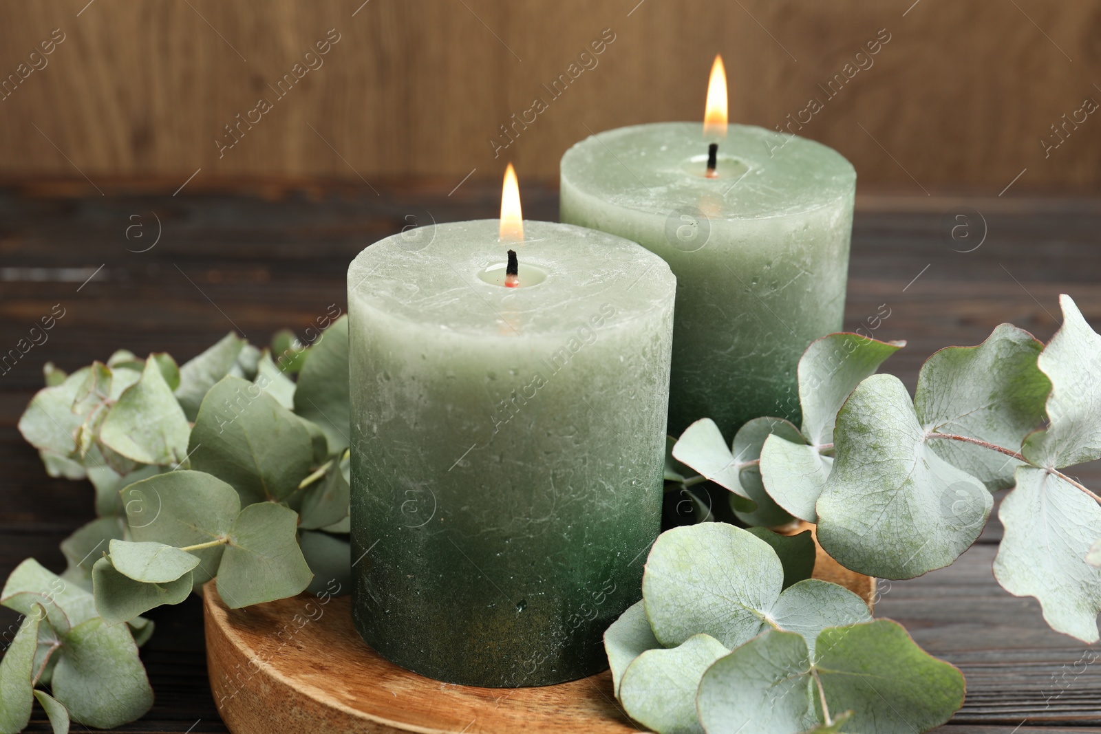 Burning candles and eucalyptus branches on wooden table, closeup Photo of Burning candles and eucalyptus branches on wooden table, closeup